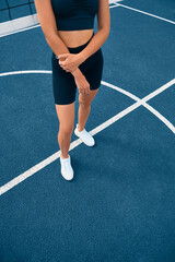 Camera focus on sneakers and floor. White sneakers on the legs of a European sports girl. Fitness girl model stands on the sports ground