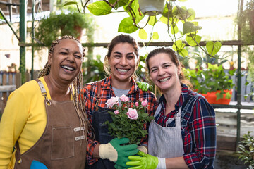 Happy multiracial female gardeners working in plants and flowers garden shop