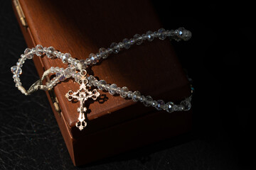 Rosary and cross made of clear colored beads on a wooden box.