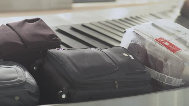 Close-up shot of various luggage and suitcases moving from left to right on an airport conveyor belt in Asia. Captured inside a terminal, this dynamic scene shows travel, transit, and transportation
