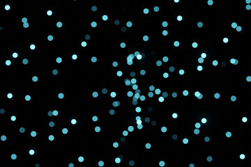 Defocused bokeh lights on black background, an abstract naturally blurred backdrop for Valentines Day or birthday party. Festive light texture. Violet blue garland in blur. Color 2022