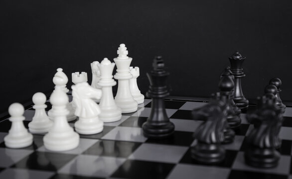 The king in a battle chess game stands on a chessboard with a black isolated background. Business Leadership Ideas.