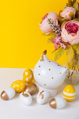 Easter eggs, ceramic chicken and a bouquet of flowers on a yellow background. Happy easter concept.