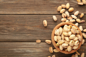 Pile of Pistachios on wooden bowl, pistachios on grey wooden background. Vetical photo.