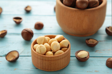 Macadamia nuts on wooden bowl on blue background. Top view.