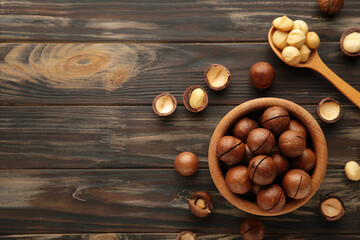 Macadamia nuts on wooden bowl on brown background. Top view.