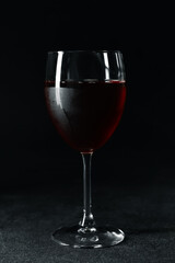 Glass of tasty red wine on dark background