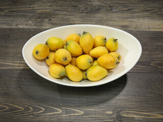 A bowl with ripe loquats or Japanese plums.