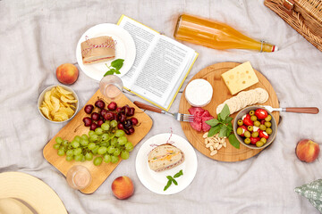 leisure, food and drinks concept - close up of snacks and picnic basket on blanket on grass at summer park