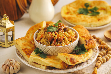 Bowl with tasty Asian pilaf and flatbread on table