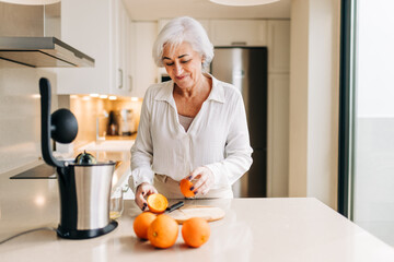 Happy senior woman making fruit juice using an electric blender