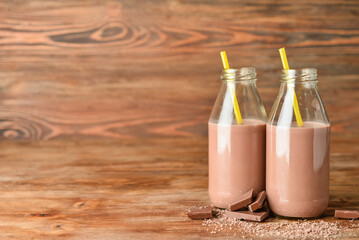 Bottles of delicious chocolate milk on wooden background