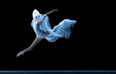 Graceful classic ballerina dancing with weightless fabric isolated on black studio background in...