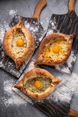 three ajar khachapuri with meat egg cheese on a dark wooden table flat lay, three different...