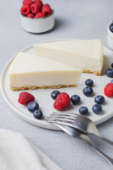 Classic New York cheesecake with fresh raspberries and blueberries on a concrete background, close up. Soft selective focus