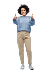 people, fashion and style concept - happy smiling woman in blue sweater and jeans showing thumbs up gesture over white background