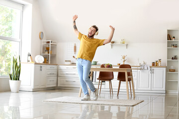 Cool young man dancing and listening to music at home