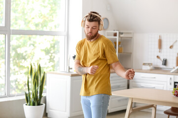 Cool young man dancing and listening to music at home