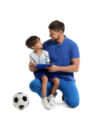 Male trainer with little boy and soccer ball on white background