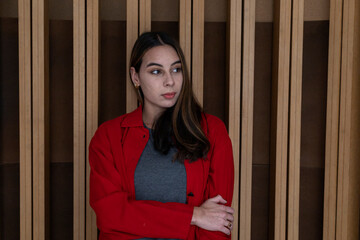 Portrait of young woman (23) Latin American with relaxed attitude. Background of wooden slats. He wears red sweater. Portrait concept.