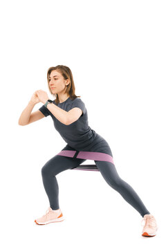 Vertical photo of a young woman performing side squats over white background.
