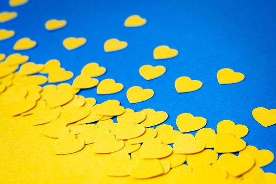 Papercut concept with yellow paper hearts forming an ukrainian flag motive on the blue background.