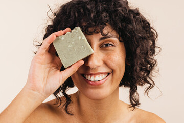 Happy young woman holding a bar of natural soap - obrazy, fototapety, plakaty