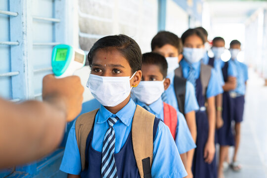 School kids with medical face mask being test with temperature before entering to classroom - concept of coronavirus covid-19 safety measures, healthcare safety and back to school. - Powered by Adobe