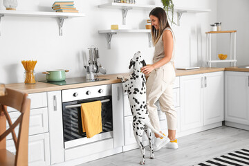 Young woman with Dalmatian dog in kitchen