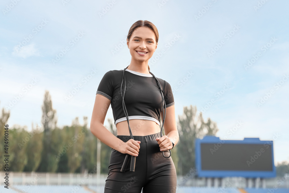 Poster Sporty young woman with skipping rope outdoors