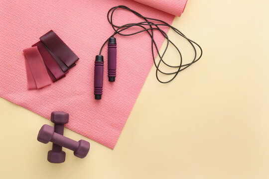 Sports equipment and yoga mat on color background
