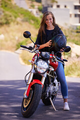 Naklejka na ściany i meble Are you ready to ride. An attractive young woman sitting on her motorcycle holding her helmet.