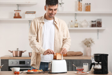 Young man making tasty toasts in kitchen