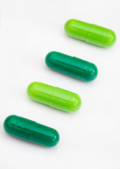 light and dark green medicine capsules in diagonal line, isolated on white with copy space