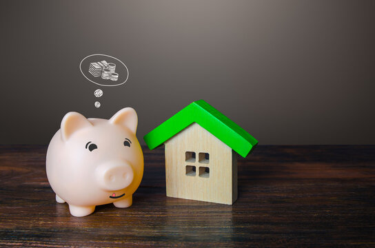 Pig piggy bank dreams of making money by selling a house. Savings and economy on utilities bills, energy efficiency of the building. Rental business. House for rent. Property valuation.