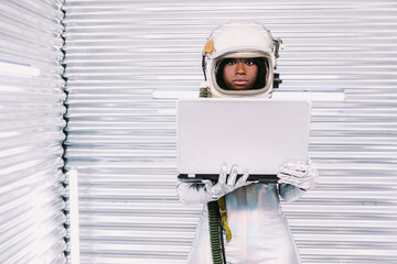 Black astronaut browsing laptop in spaceship