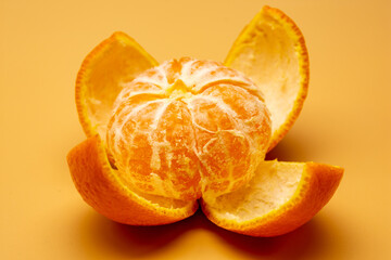 Closeup of a peeled juicy, sweet mandarin on the orange surface