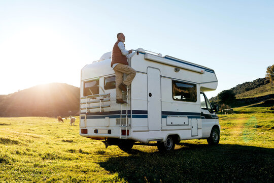 Man on ladder of camper in nature