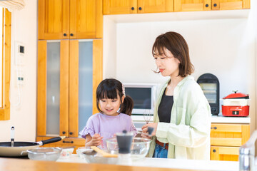 お母さんと一緒に料理をする小さな女の子