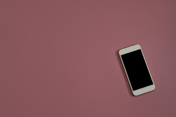 Top view flat lay of a smartphone with blank screen on a orchid pink background with a lot of empty space for social media and technology concept.