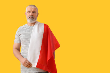 Mature man with flag of Poland on yellow background
