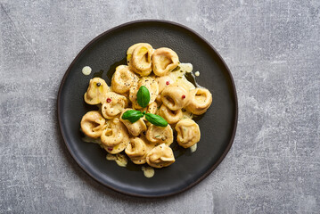 Tortellini ravioli creamy pasta. Italian ravioli pasta with pumpkin and basil on rustic background