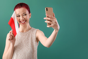 Beautiful young woman with flag of Poland taking selfie on green background