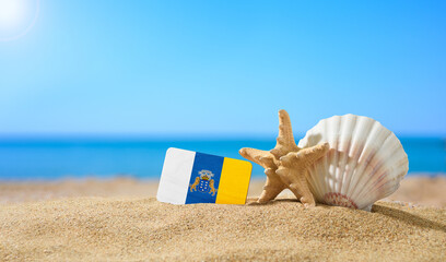 Tropical beach with seashells and Canaries flag. The concept of a paradise vacation on the beaches of Canaries.