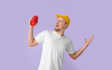 Man holding wireless portable speaker and singing on violet background