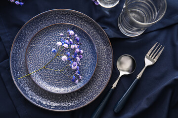 Elegant table setting with flowers on dark fabric background