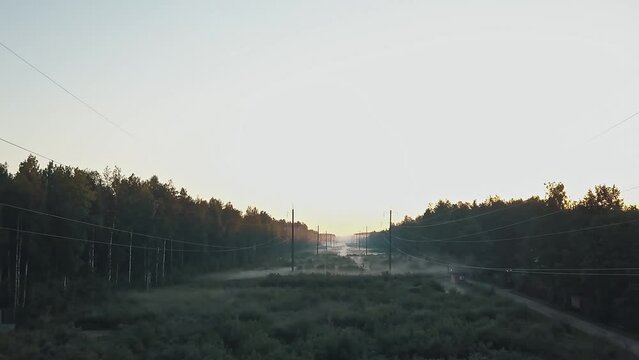 High voltage power line in the forest in fog in the morning