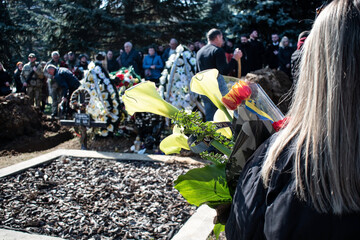 Girl holds Ukrainian mourning flowers. Funeral of the Ukrainian military. Civil and military at the...