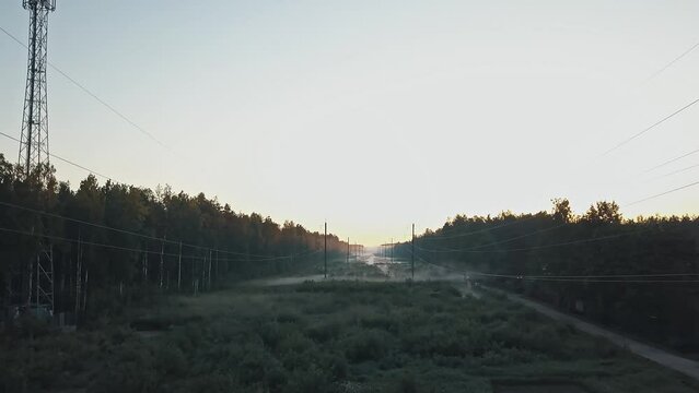 High voltage power line in the forest in fog in the morning