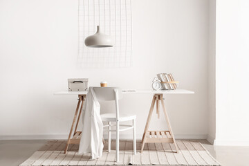 Interior of light room with comfortable workplace near white wall